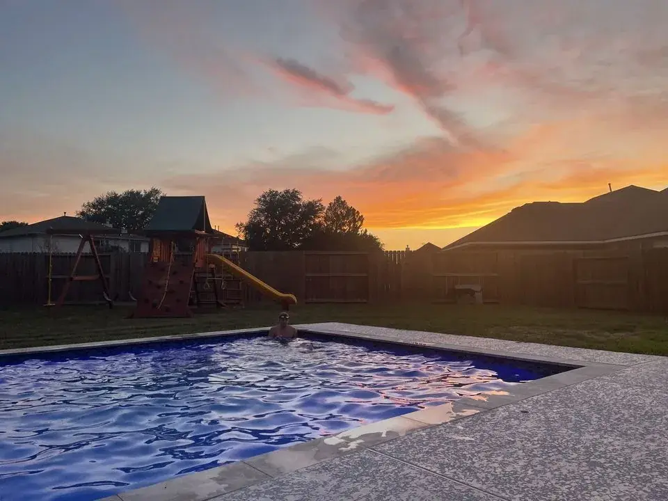 Custom inground swimming pool at sunset in an East Texas backyard, built by Sam Houston Pools and Outdoors
