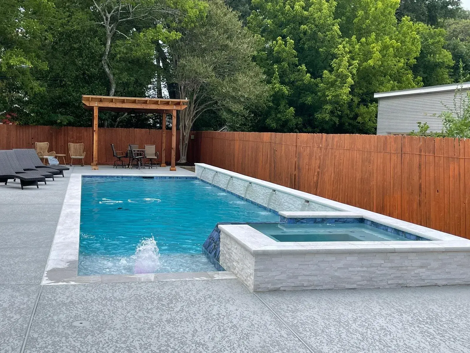 Modern pool and spa combination with stacked stone waterfall feature in a Houston-area custom build